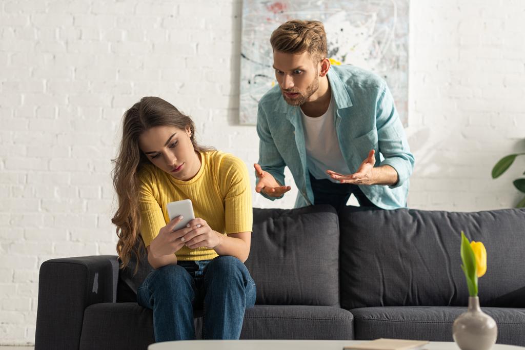 angry-man-quarreling-smartphone-depended-girlfriend-couch