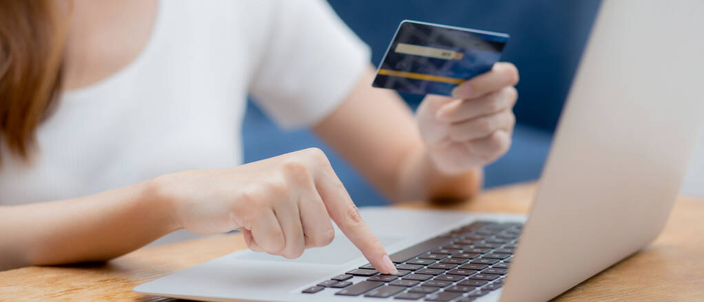 Hand of young woman holding credit card buying shopping online w